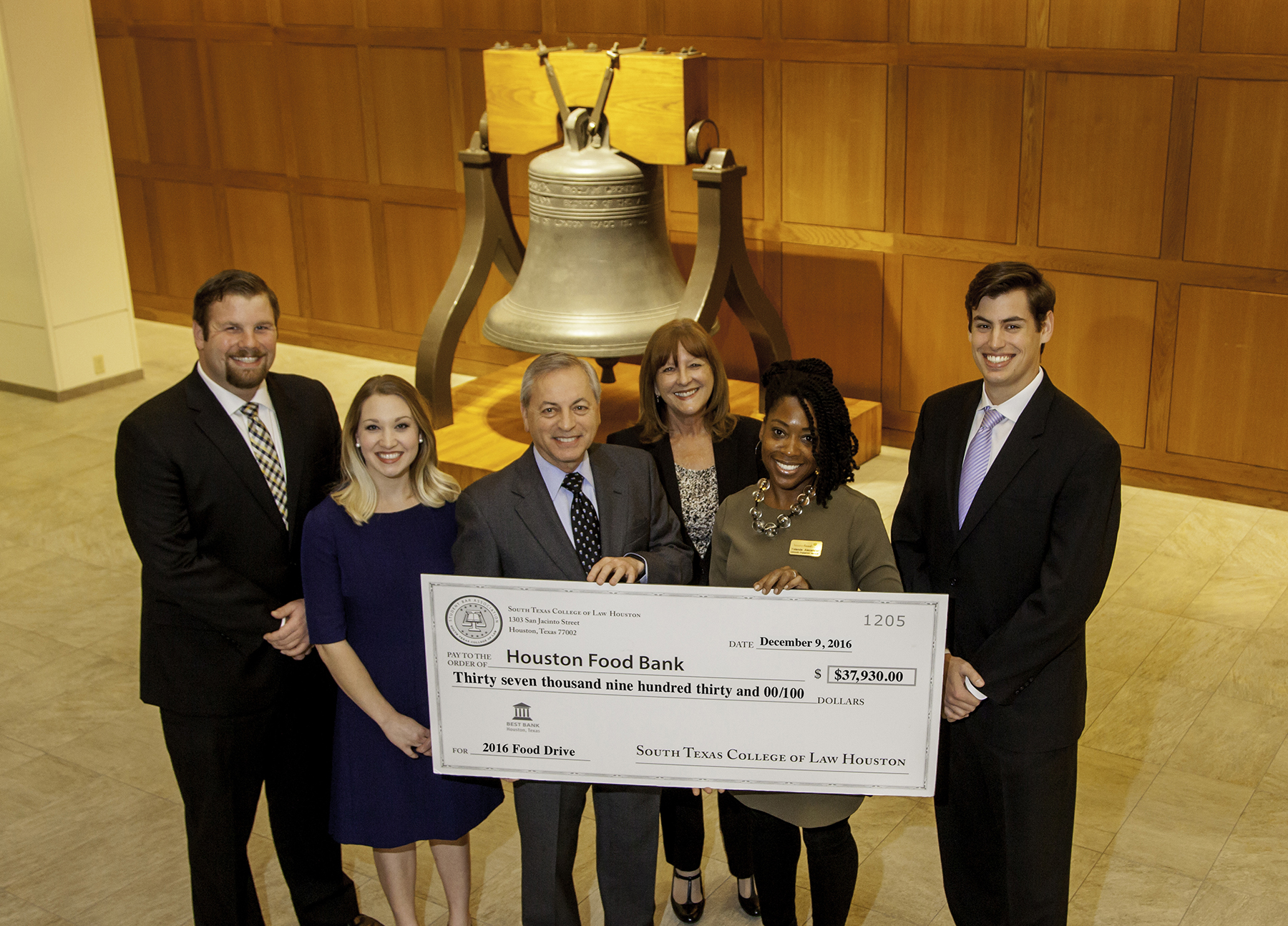 Student Bar Association (SBA) leaders Cara Woolet, Taylor Christie, and Earl Ingle – along with President and Dean Donald J. Guter, Dean Wanda Morrow, and Houston Food Bank Community Engagement Manager Yolanda Alexander gather in the law school's atrium holding an oversize check for $38,000, which the law school raised for the Houston Food Bank's holiday food drive.